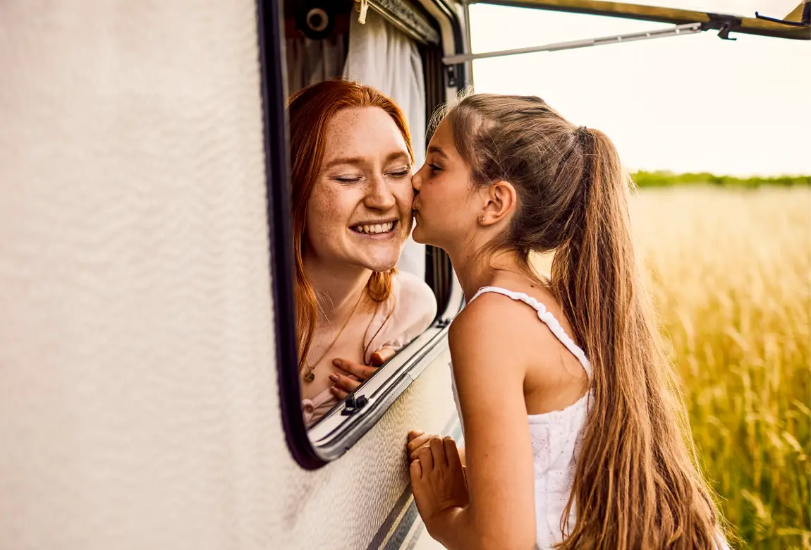 Mädchen bekommt ein Küsschen von jüngerer Schwester. Familienglück mit Langnese Honig.